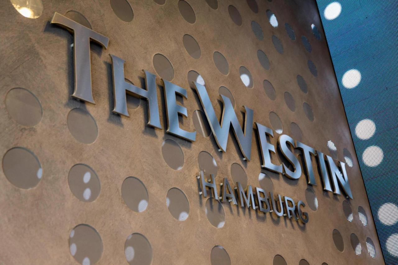 Hotel The Westin Hamburg Elbphilharmonie Exterior foto The image shows a decorative wall featuring the logo of "The Westin Hamburg." The logo is prominently displayed in a sleek, silver font. The background has a textured surface with circular patterns, adding a modern and elegant touch to the overall ap