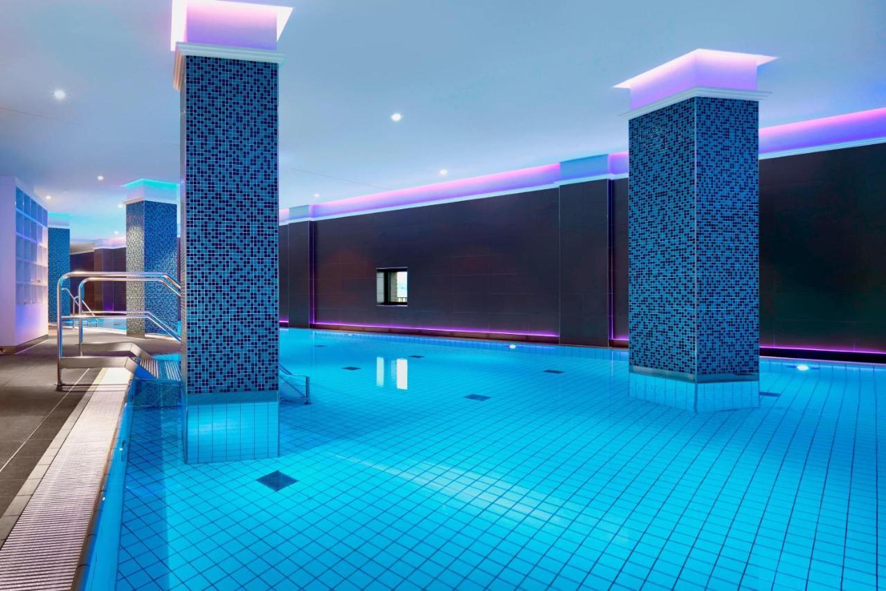 Hotel The Westin Hamburg Elbphilharmonie Exterior foto The image shows a swimming pool area that features a modern, upscale design. The pool has bright blue tiles reflecting the water, creating a vibrant atmosphere. There are two columns dressed in a similar blue tile pattern, and the walls are adorned w